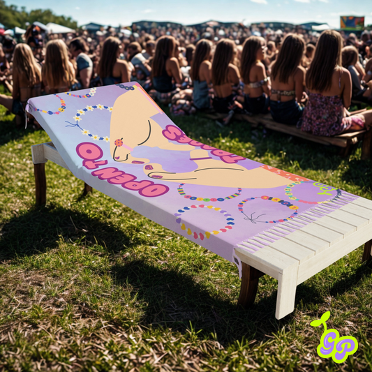 Pashmina with cartoon hands forming a heart and kandi bracelets laid on a wooden lounge chair at an outdoor music festival.