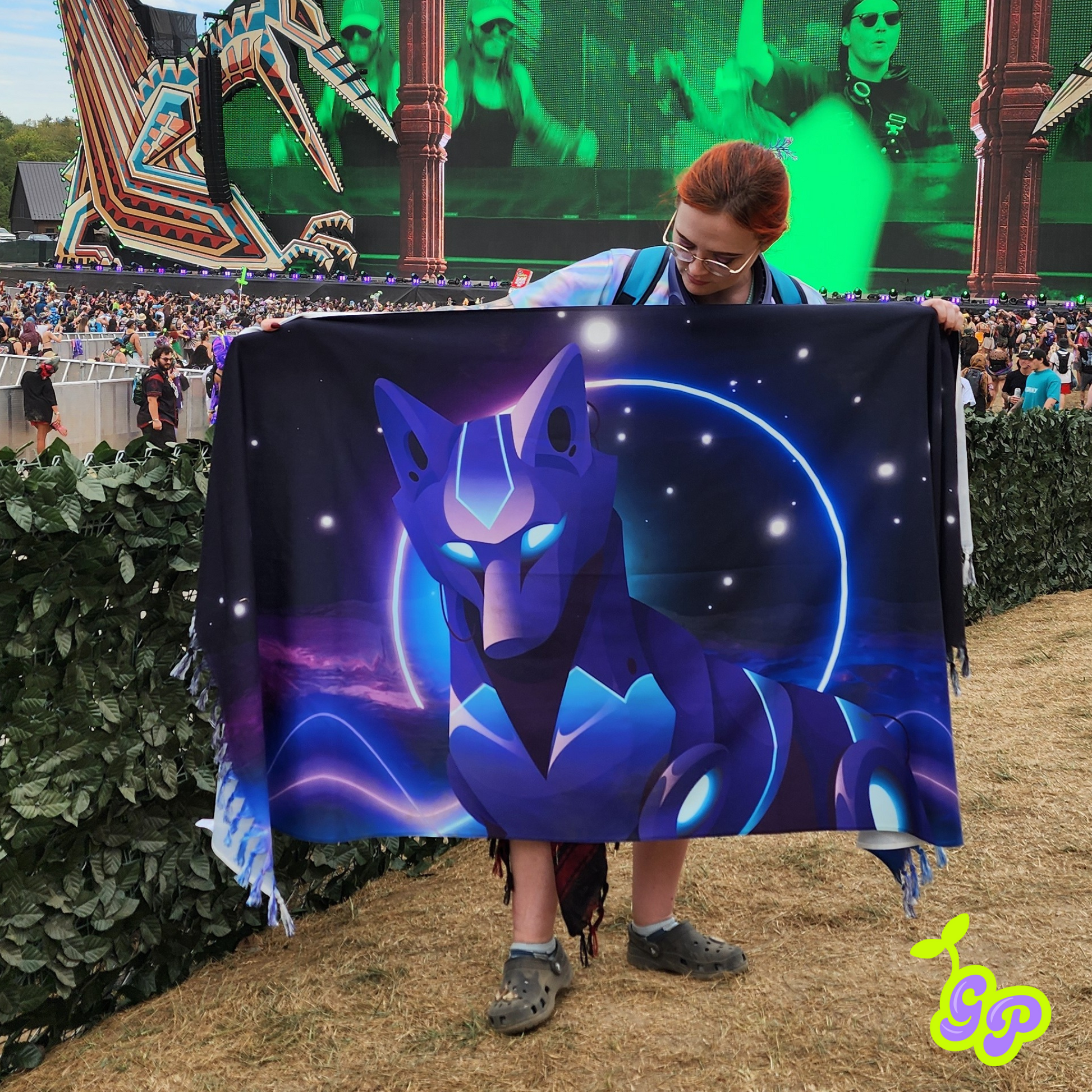 Female rave-goer holding the neon cyber wolf rave pashmina while standing in front of Lost Lands music festival main stage in order to demonstrate size. 